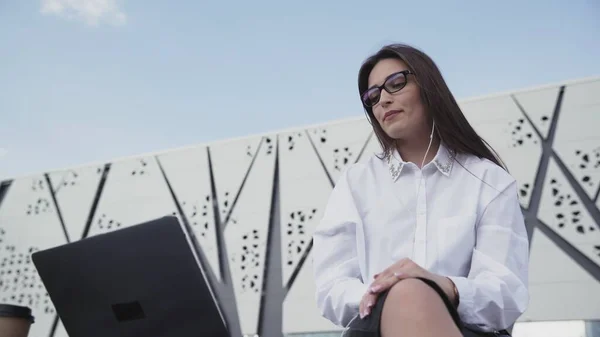 Young caucasian business woman with long hair using laptop sitting outdoor. — Stock Photo, Image