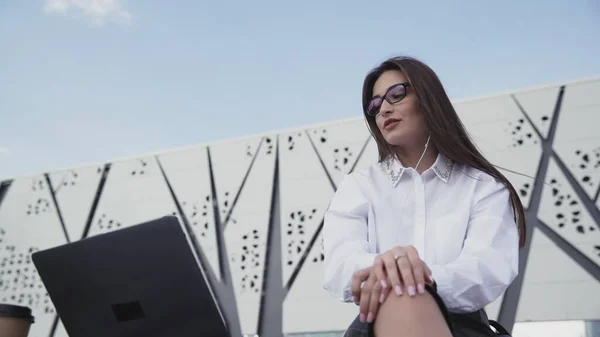 Молода біла ділова жінка з довгим волоссям, використовуючи ноутбук, що сидить на відкритому повітрі . — стокове фото