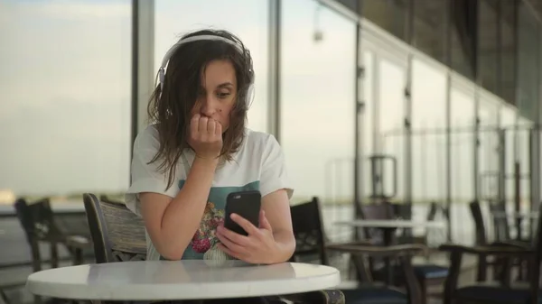 Jonge vrouw in hoofdtelefoon op zoek naar de smartphone — Stockfoto