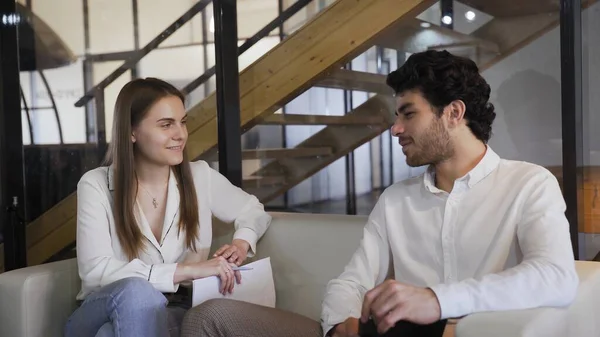 Young elegantly dressed couple sitting on a white sofa and talking. — Stock Photo, Image