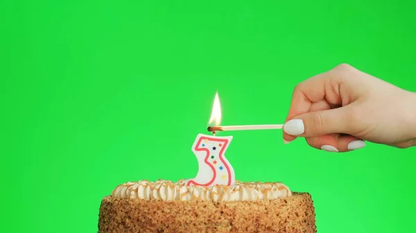 Зажигание свечи дня рождения номер четыре на вкусном торте, зеленый экран 3 — стоковое фото