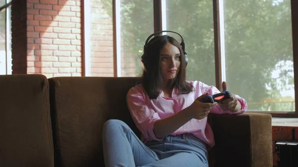 Jeune femme avec écouteurs jouer à un jeu vidéo en utilisant joystick — Photo