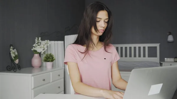 Молода приваблива і нудна жінка працює на ноутбуці в спальні вдома — стокове фото