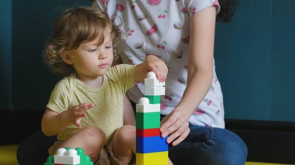 Lockig flicka gör konstruktion av leksak tegel — Stockfoto