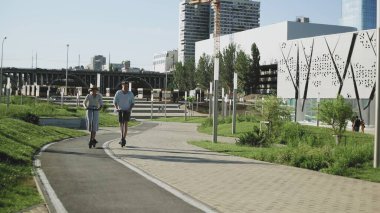 Mutlu çift yaz parkında elektrikli scooterlarına biniyor.