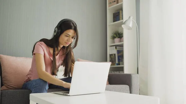 Smiling young woman with headphones listening music and surfing Internet at home — Stock Photo, Image