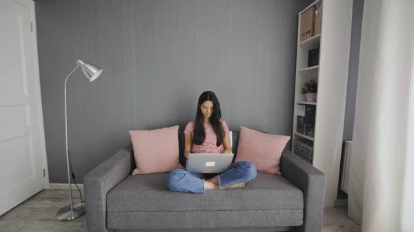 Eine attraktive Frau arbeitet auf einer Couch an ihrem Computer — Stockfoto