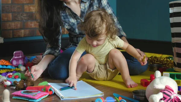 Anne ve kızı yere bir defter çiziyor.