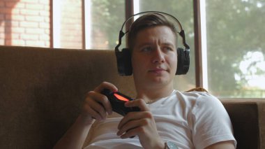 Kulaklıklı bir adam video oyunu oynuyor.