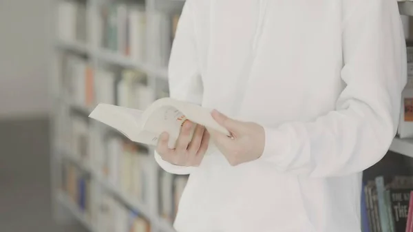 Studentmannen leser bok i biblioteket – stockfoto