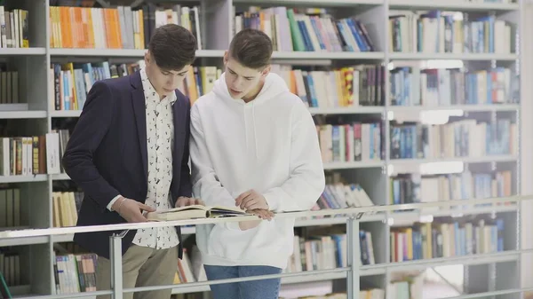 Jóvenes estudiantes con libros preparándose para el examen en la biblioteca —  Fotos de Stock