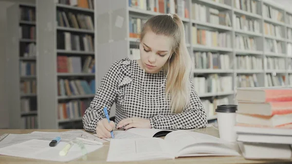 Молода студентка пише підручники в бібліотеці — стокове фото