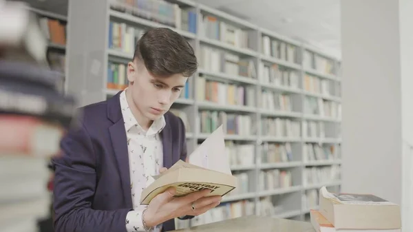 Fiatal diák keményen tanul a könyvtárban. Férfi egyetemi hallgató csinál tanulmányi kutatást a könyvtárban könyvek — Stock Fotó