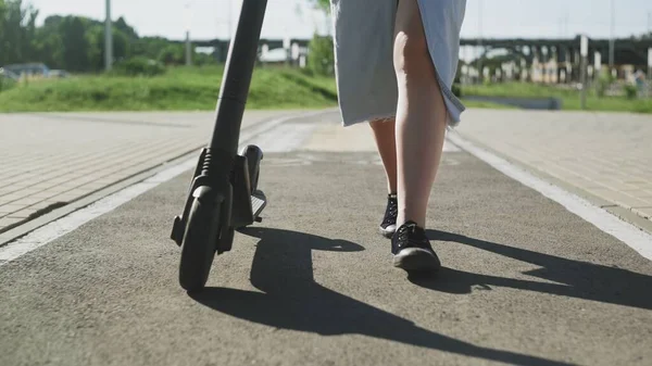 Close para arriba de piernas femeninas y el scooter eléctrico de la patada — Foto de Stock