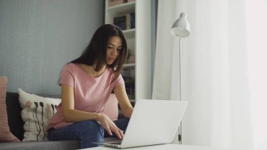 Genç kadın dizüstü bilgisayara bakıyor ve yazıyor.