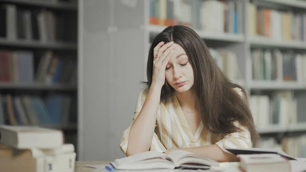 Fáradt fiatal nő készül vizsgázni az egyetemi könyvtárban — Stock Fotó