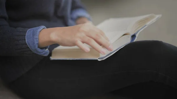 Close up of Young african american woman is reading book sitting on floor in university library. — Stock Photo, Image