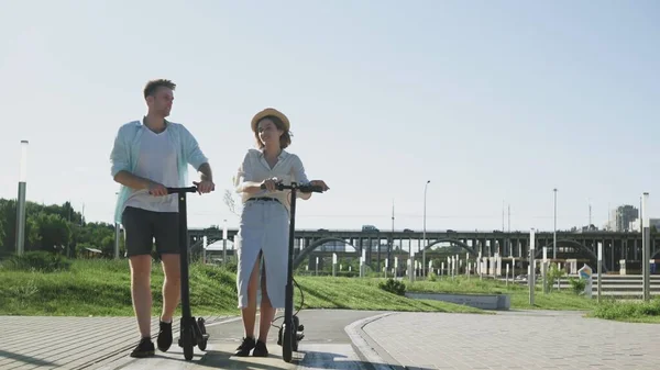 Jeune couple avec scooters électriques à une date dans le parc d'été — Photo