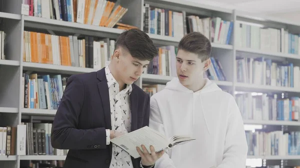 Jóvenes estudiantes con libros preparándose para el examen en la biblioteca —  Fotos de Stock