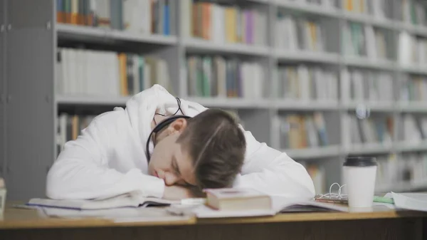 Fatigué gars s'endort tout en étudiant à la bibliothèque à l'université — Photo