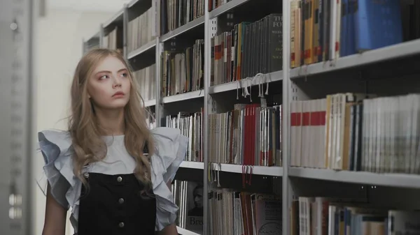 Beautiful young blonde student girl in school library — Stock Photo, Image