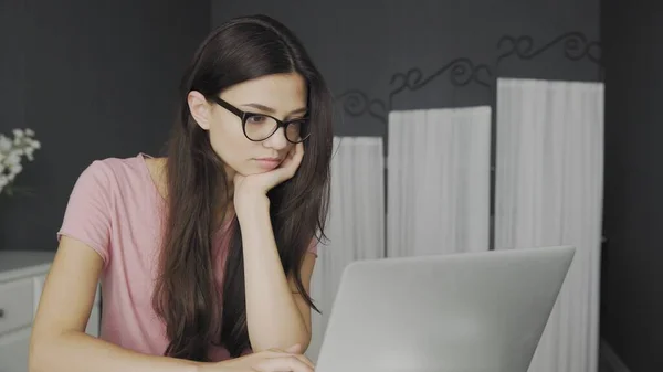 Красива студентка в окулярах навчається на ноутбуці вдома — стокове фото