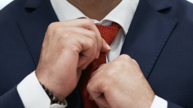 İşadamı, beyaz gömlekli kırmızı kravatı düzeltiyor.