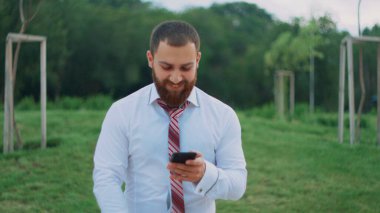 Çekici iş adamı cep telefonuna bakıyor, mutlu hissediyor, iyi haberler görüyor..