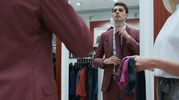 Young businessman looks at the mirror and trys on different ties — Stock Photo, Image