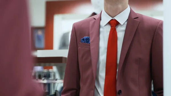 Νεαρός επιχειρηματίας κοιτάζει στον καθρέφτη είναι κατάστημα κοστουμιών — Φωτογραφία Αρχείου