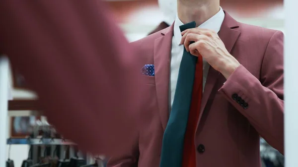 Young businessman looks at the mirror and trys on different neckties — Stock Photo, Image