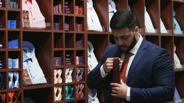 Bearded man dressed in elegant suit chooses his tie — Stock Photo, Image