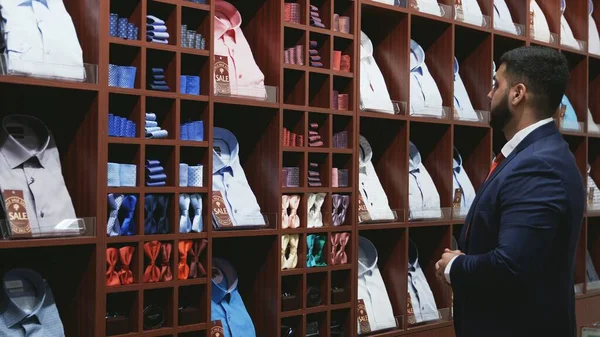Бизнесмен в синей куртке выбирает галстук в магазине — стоковое фото