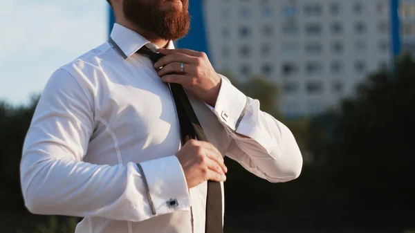 Empresário de camisa branca amarrando a gravata ao ar livre — Fotografia de Stock