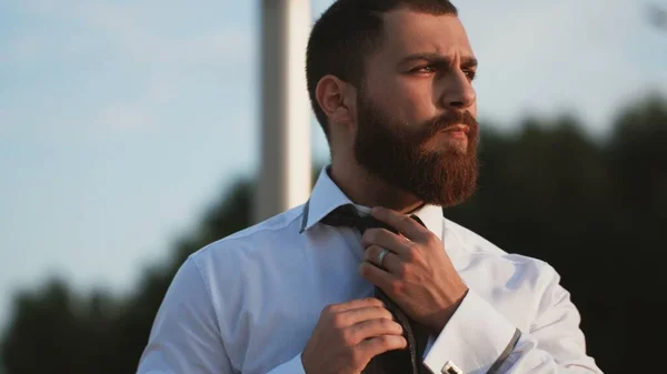 Jóképű férfi fehér ingben, nyakkendőt kötözve a szabadban. — Stock Fotó