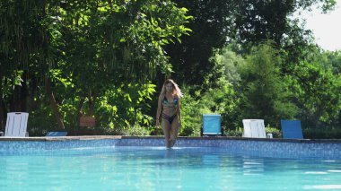 Seksi kadın havuza iniyor.