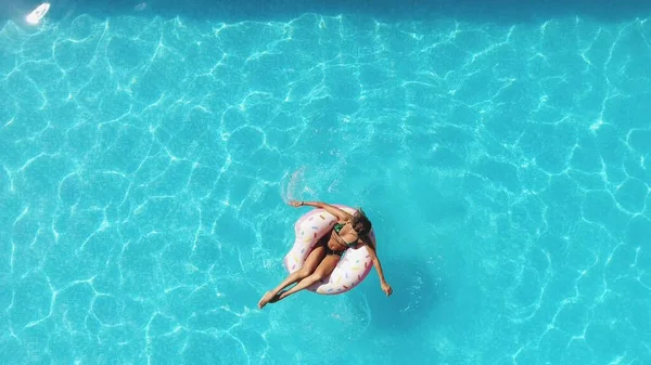 游泳池里的女孩在一个粉色的充气甜甜圈上游泳 — 图库照片