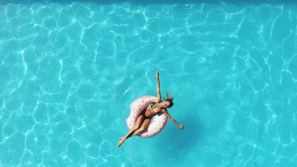 Ragazza in piscina nuota su una ciambella gonfiabile di colore rosa — Foto Stock