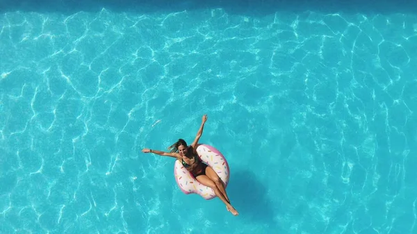 Ragazza in piscina nuota su una ciambella gonfiabile di colore rosa — Foto Stock