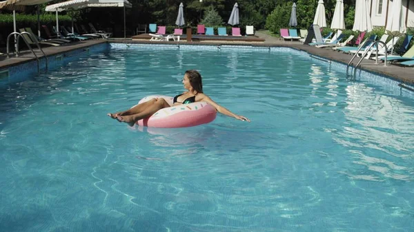 女人带着一个充气的甜甜圈漂浮在汹涌的游泳池里 — 图库照片