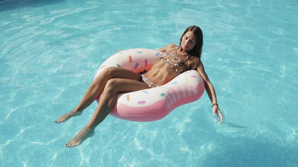 Γυναίκα χαλαρώνει σε φουσκωτό ροζ ντόνατ επιπλέουν στην πισίνα — Φωτογραφία Αρχείου