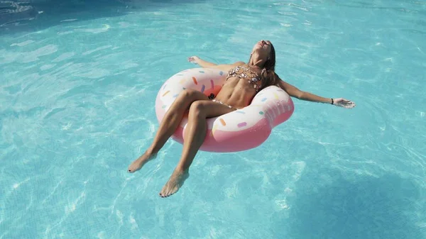 Mujer es relajante en inflable rosado donut float en piscina —  Fotos de Stock