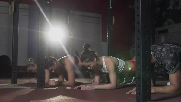 Pemuda sporty menarik orang melakukan papan latihan di matras di gym crossfit. — Stok Foto