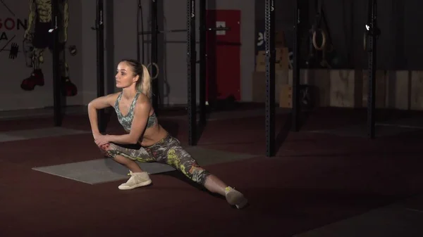 Fitness žena protahuje svaly před tréninkem v crossfit tělocvičně. — Stock fotografie