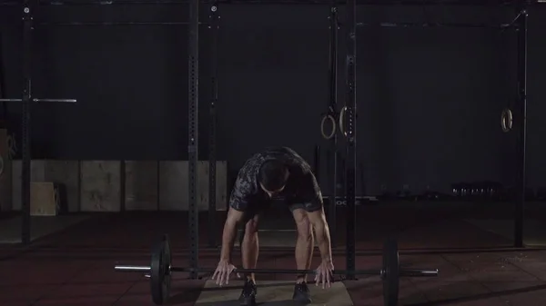 Człowiek wykonujący ćwiczenia deadlift z sztangą. Pewny siebie młody człowiek robi trening podnoszenia ciężarów sztanga na crossfit siłowni. — Zdjęcie stockowe