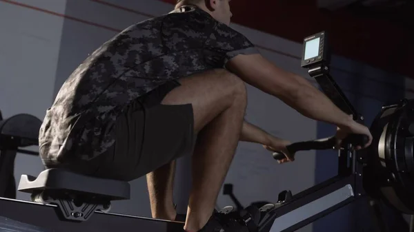 Young Fit Man Working Out on Rowing Machine at cross gym Stock Photo