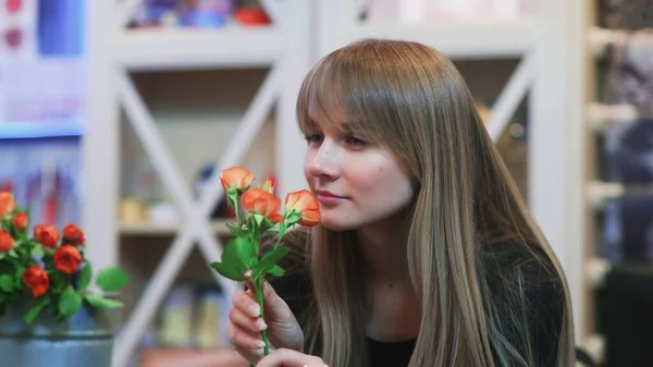 A young woman smelling a flower in a shop — Stock Photo, Image