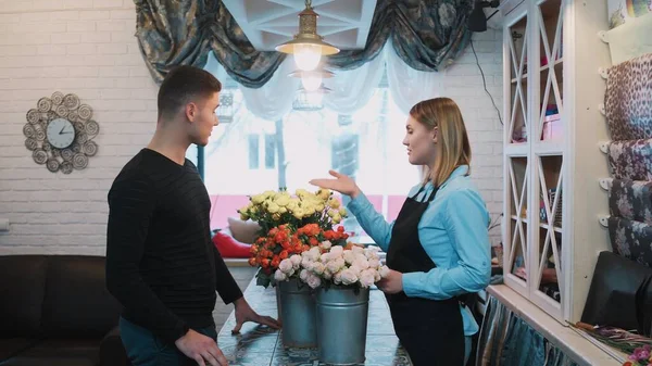 Hombre guapo ven a una floristería y pregunta a la floristería sobre las flores — Foto de Stock