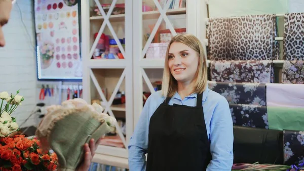 The girl florist is selling a bouquet to the Man florist owner of shop — Stock Photo, Image