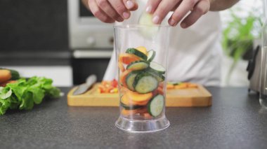 Adam blendere doğranmış sebze koyuyor.